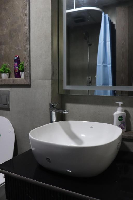 een witte wastafel op een zwart aanrecht in een badkamer bij High Sky inn in Noida