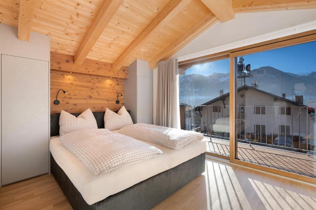 a bedroom with a bed and a large window at Villa Helena - Panorama Dolomiti in Cavalese