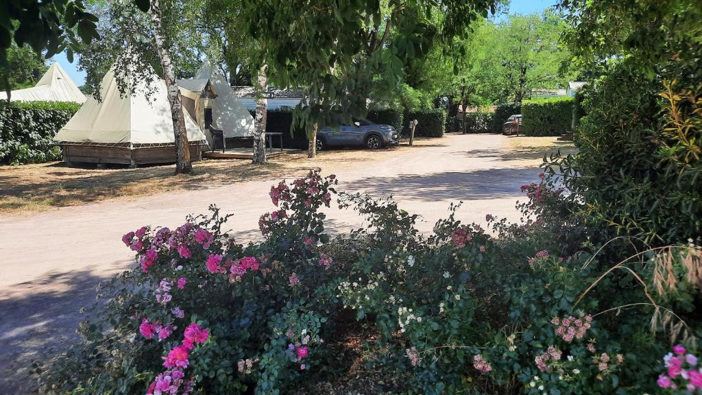Camping Au Lac d'Hautibus في Argenton-Château: حديقة فيها ورد وخيمة في ساحة