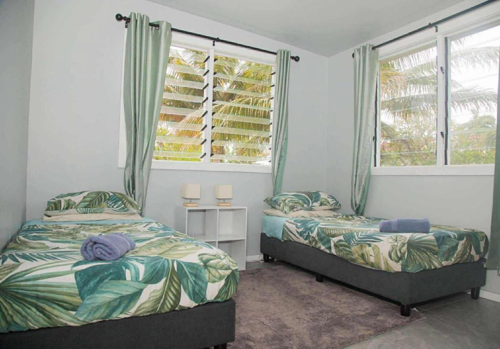 due letti in una stanza con due finestre di 2 Bedroom House - Villa Teremoana a Ngatangiia