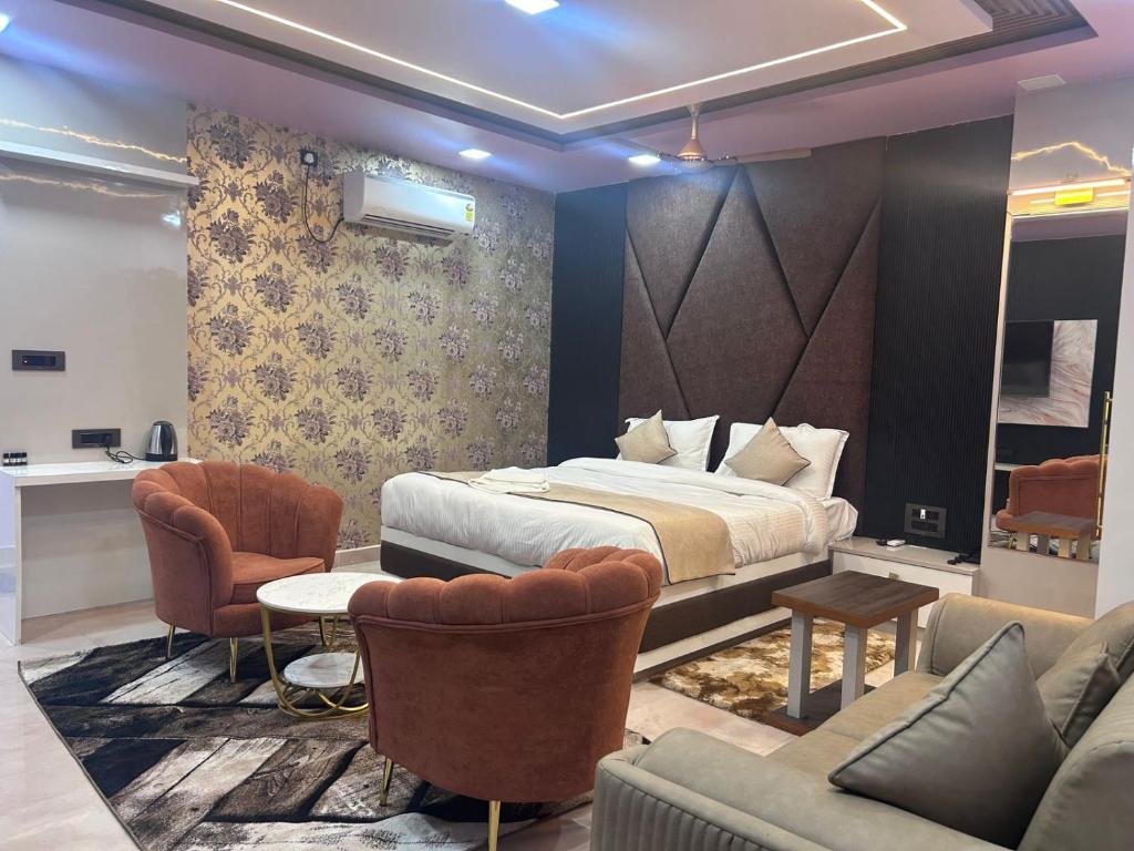 a bedroom with a bed and a couch and chairs at Hotel Rashmi Grand in Khagaria