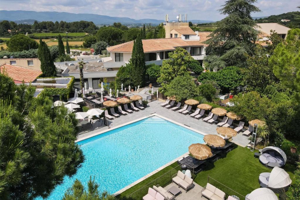 Una vista aérea de una piscina del resort con tumbonas y un resort. en Best Western Sévan Parc Hôtel, en Pertuis