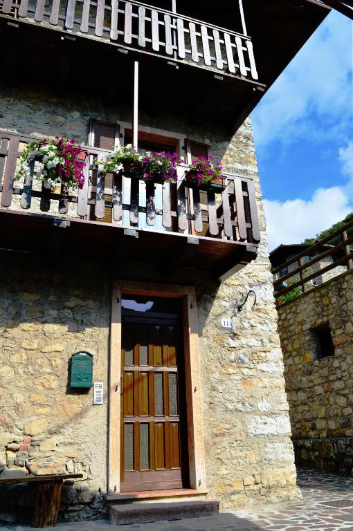 a building with a wooden door and a balcony with flowers at Casa Furletti Holiday Home in Tenno