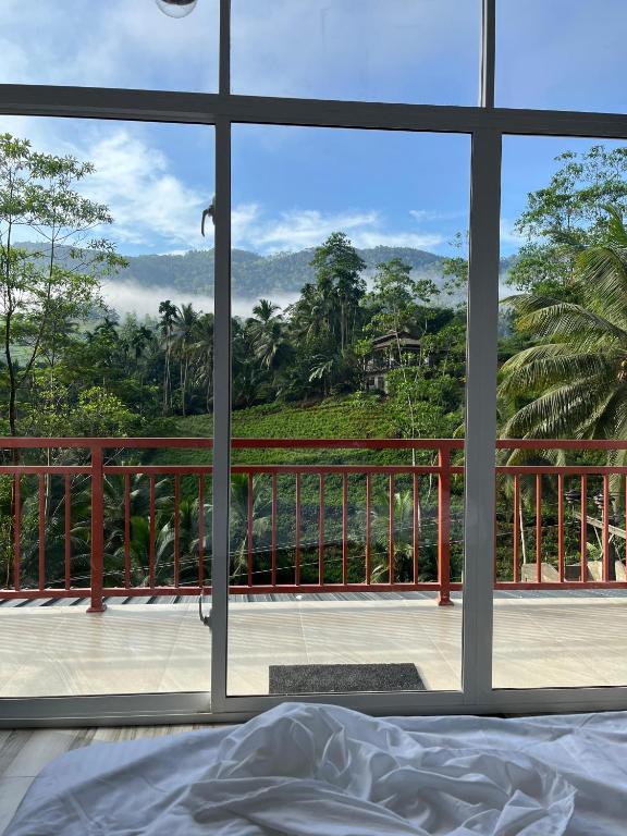 a bedroom with a view of the mountains from a window at Sinharaja Eliphinity Hotel and Restaurant in Deniyaya