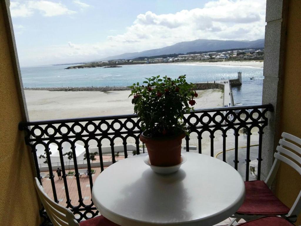 una mesa con una maceta en un balcón con la playa en Foz Playa y Mar by I Love Norte, en Foz