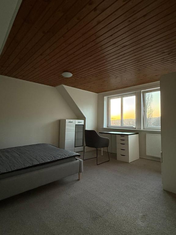 een slaapkamer met een bed en een bureau en twee ramen bij Hobro Living House in Hobro