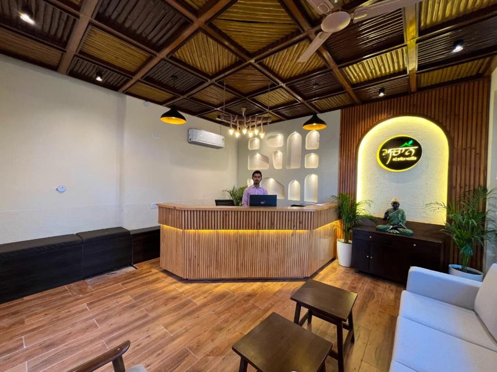 a man standing at a counter in a lobby at Muchaan Resort in Gochar