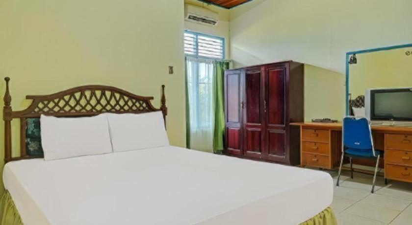 Un dormitorio con una cama, un escritorio y un televisor. en Hotel O Tri Homestay, en Palangkaraya