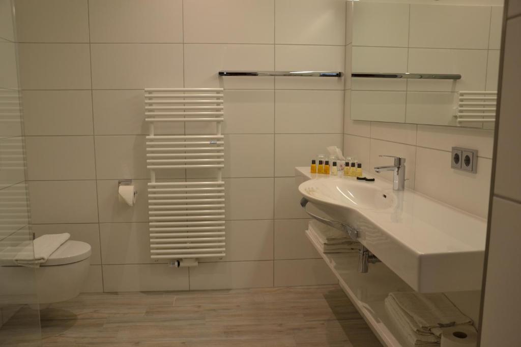 ein Badezimmer mit einem Waschbecken, einem WC und einem Spiegel in der Unterkunft Gasthof Sommer in Lautertal