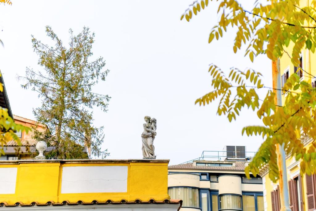 una estatua en lo alto de un edificio amarillo en Elegantis Pompeo Magno Suite Apartment - Historic Center near the Vatican and Piazza del Popolo, en Roma
