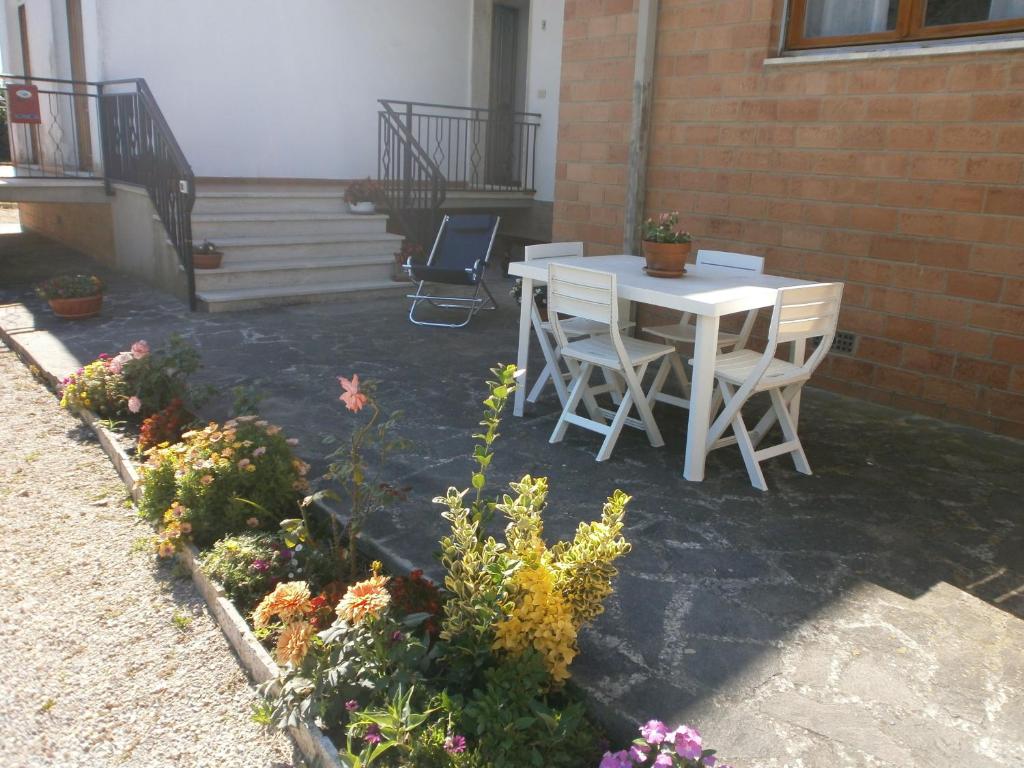 eine Terrasse mit einem weißen Tisch, Stühlen und Blumen in der Unterkunft Villetta di Campagna in Venturina Terme