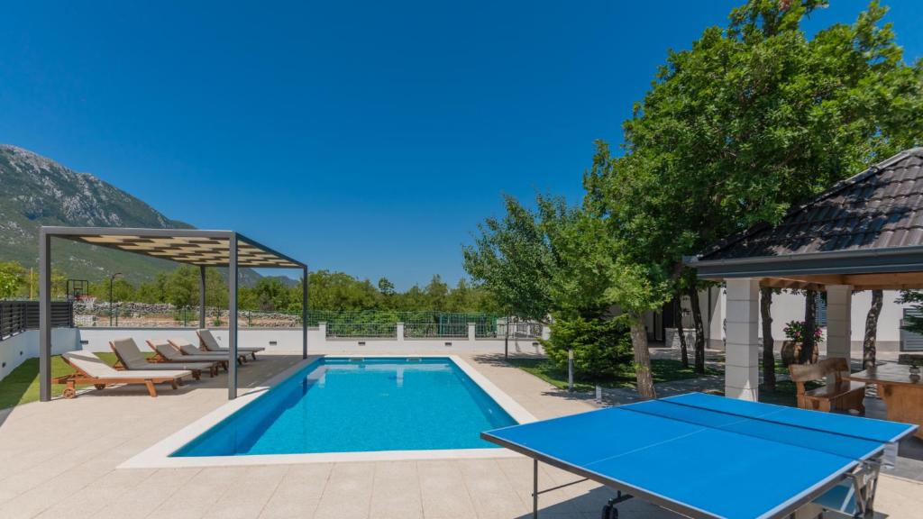 a pool with a ping pong table and a pavilion at Villa Petar Zagvozd - Makarska by Villas Guide in Zagvozd