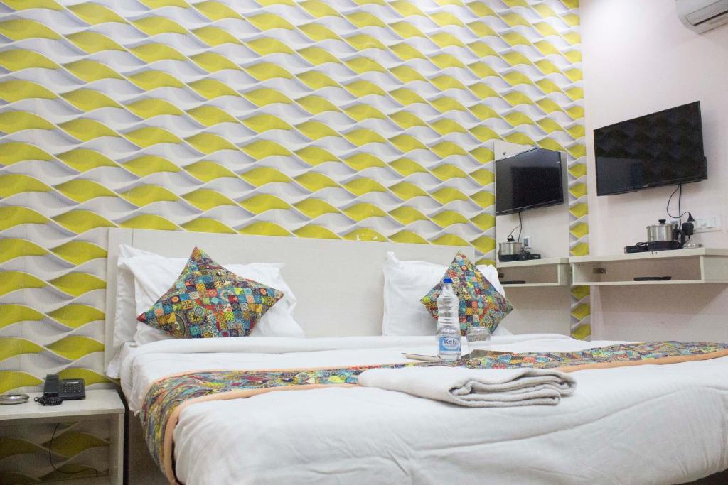 Zwei Betten in einem Zimmer mit gelb-weißer Tapete in der Unterkunft JSB Hotel in Faridabad