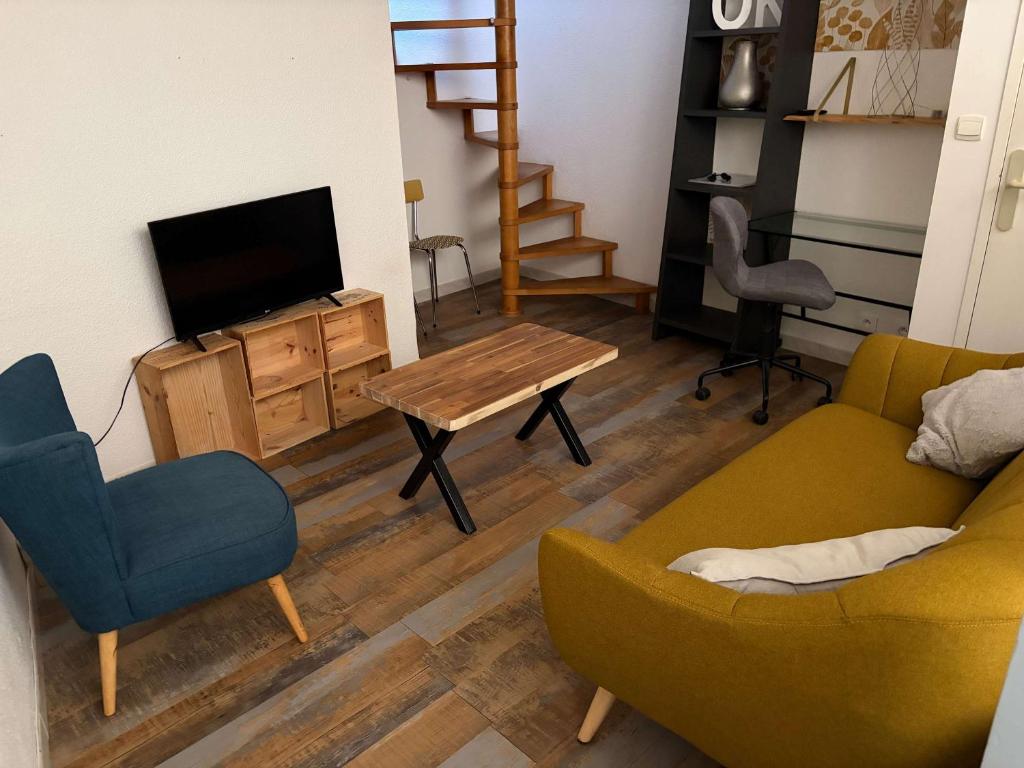a living room with a couch and a table and a tv at Charmant T2 en duplex in Bordeaux