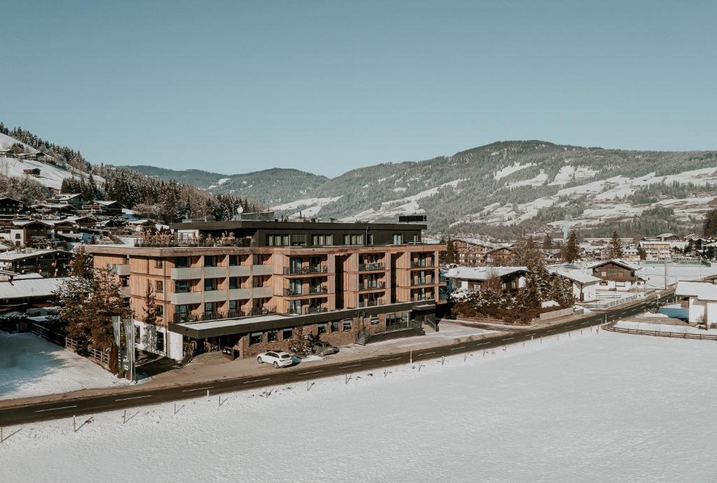 キルヒベルク・イン・チロルにあるAlpenParks Hotel & Apartment Taxacherの川の横に雪が積もった建物