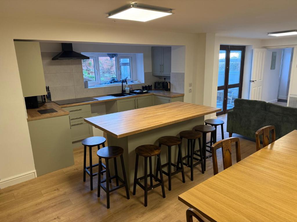 a kitchen with a large wooden island with bar stools at New 4 Bed House Sleeps up to 8 People in Chepstow