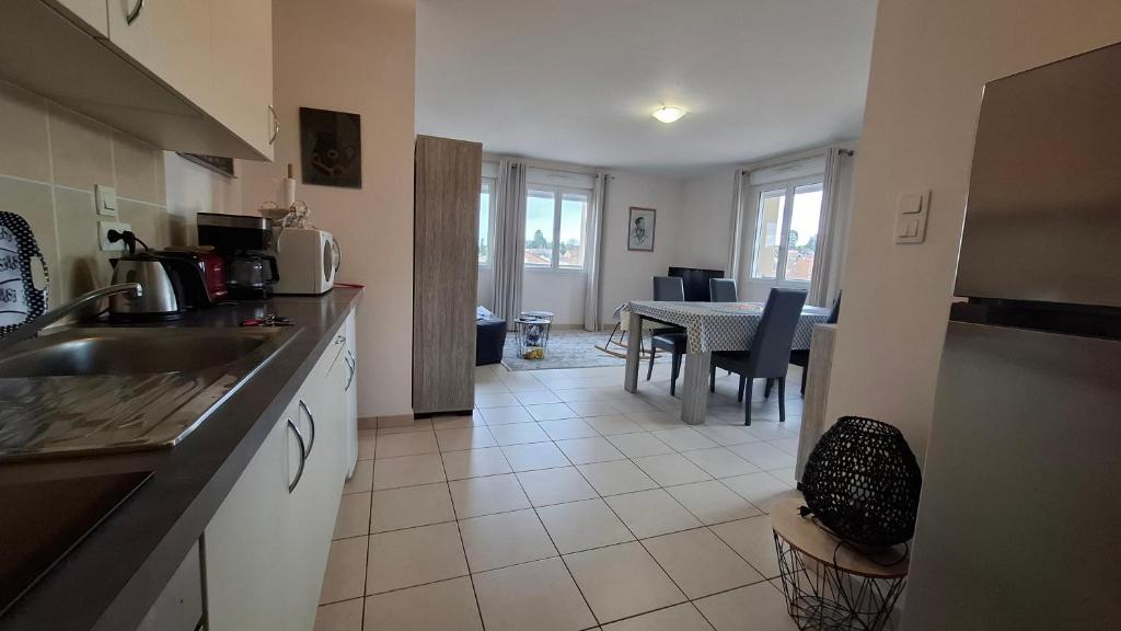 eine Küche mit Spüle und Tisch mit Stühlen in der Unterkunft Apppartement 2 pièces centre-ville in Chauffailles