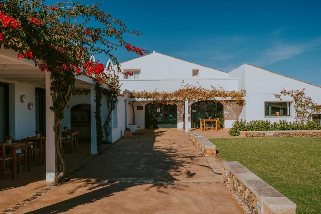 a white building with an arch with red flowers at Agroturismo Son Vives Menorca - Adults Only in Ferreries