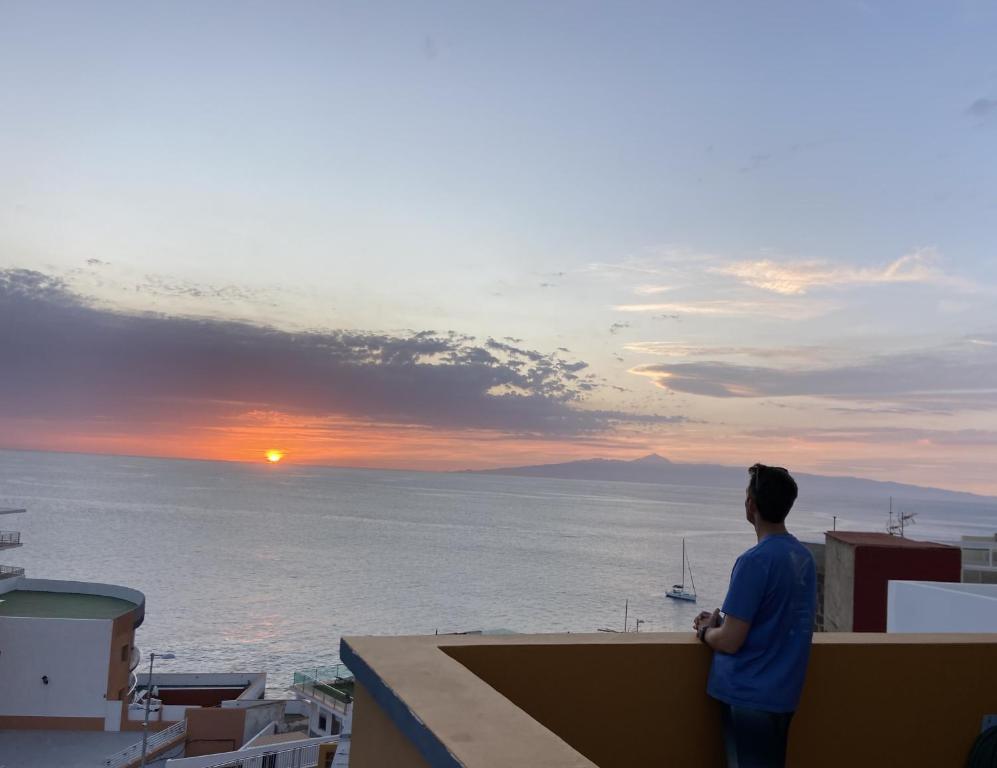 un uomo in piedi su un tetto che guarda il tramonto di Al Magec Vacacional a Sardina