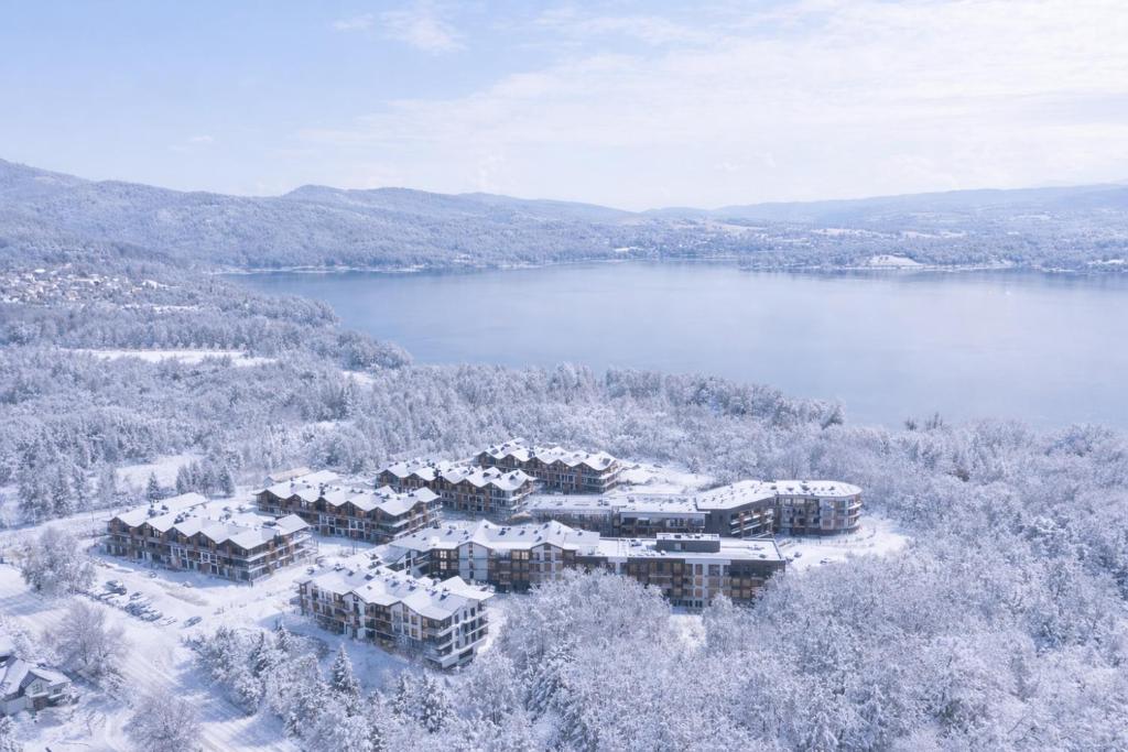eine Luftansicht eines Resorts im Schnee neben einem See in der Unterkunft Laguna Beskidów Resort in Zarzecze