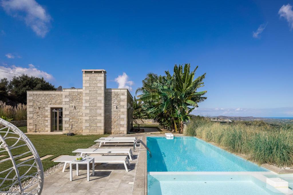 a villa with a swimming pool with tables and chairs at Thalmargia Villas, with Pool, Hot Tub & Ultimate Peace, By ThinkVilla in Garazo