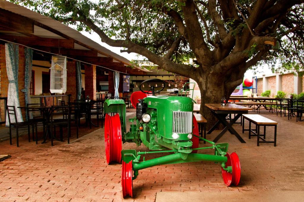 um tractor verde estacionado em frente a uma árvore em Casa Forno Country Hotel em Otjiwarongo