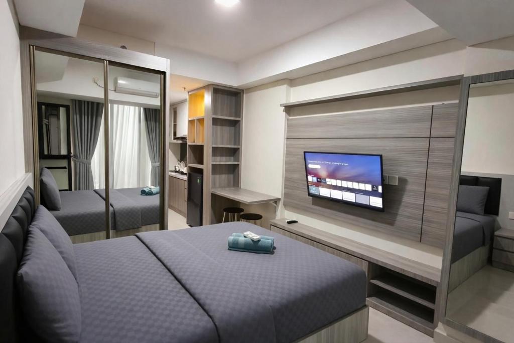 Un dormitorio con una cama y un televisor de pantalla plana. en SleepRest @ Pollux Habibie, en Batam Centre