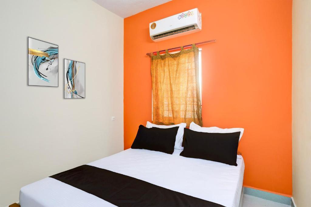 ein Schlafzimmer mit einem Bett mit einer orangefarbenen Wand in der Unterkunft Hotel O Rela Hospital Chromepet Formerly Sri Ram Ganesh Residency in Chennai