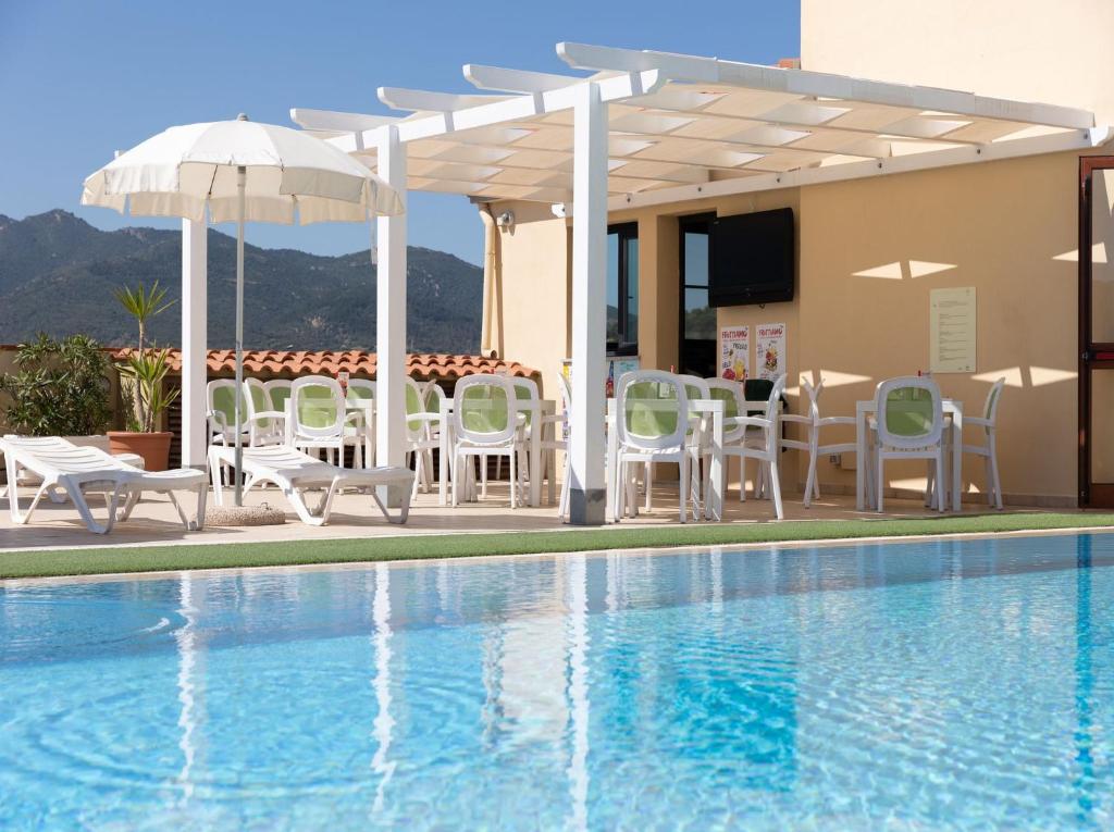 a pool with chairs and umbrellas next to a building at Premium apartment in Villasimius in Villasimius