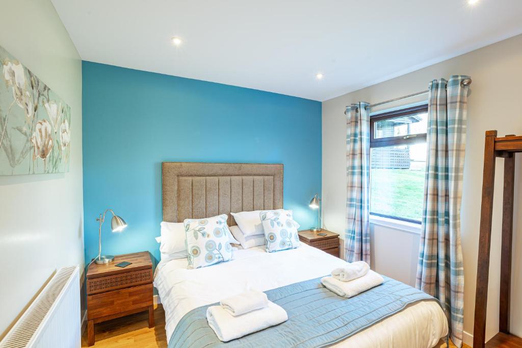 a bedroom with a large bed with blue walls at Birch Lodge 15 in Newton Stewart