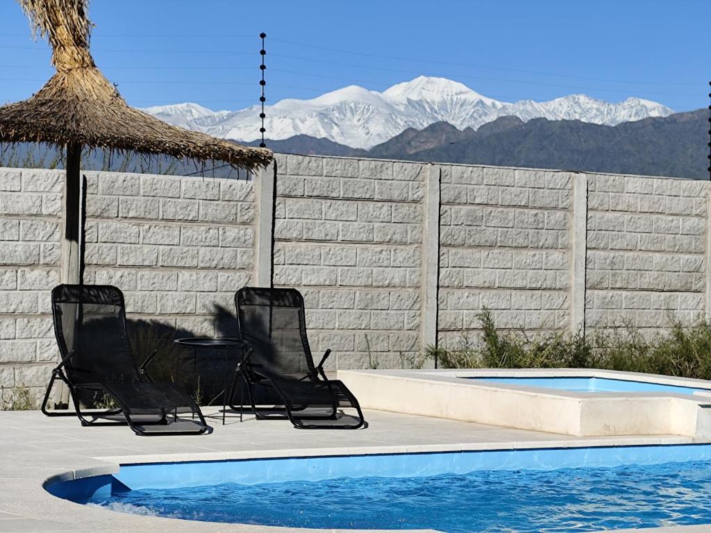 twee stoelen en een parasol naast een zwembad bij Posada Los Chañares in Ciudad Lujan de Cuyo