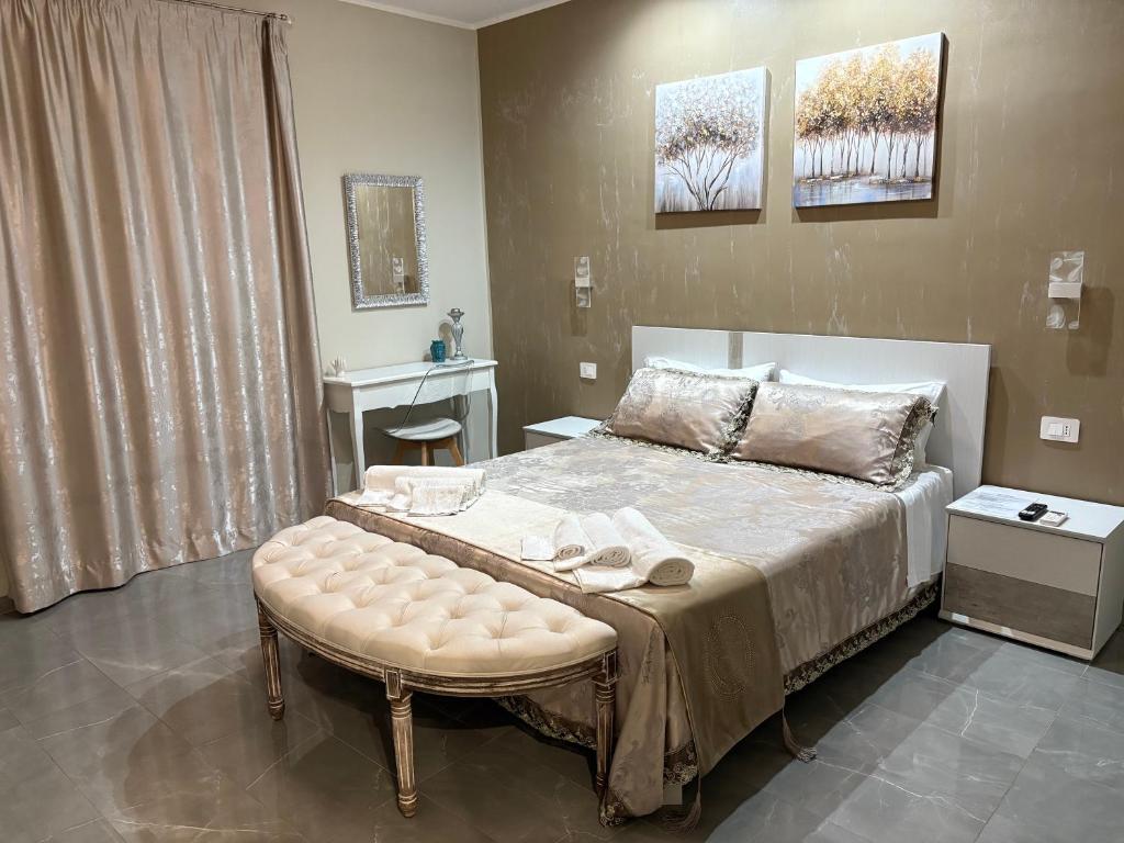 a bedroom with a bed with a bench and a table at B&B Kairos Itala in Itala