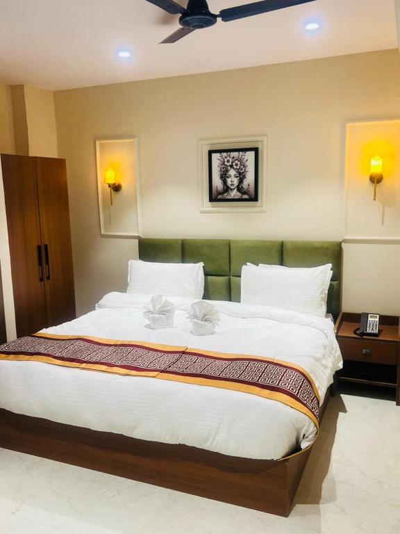 a bedroom with a large bed with a ceiling fan at Hotel Supreme Inn in Varanasi