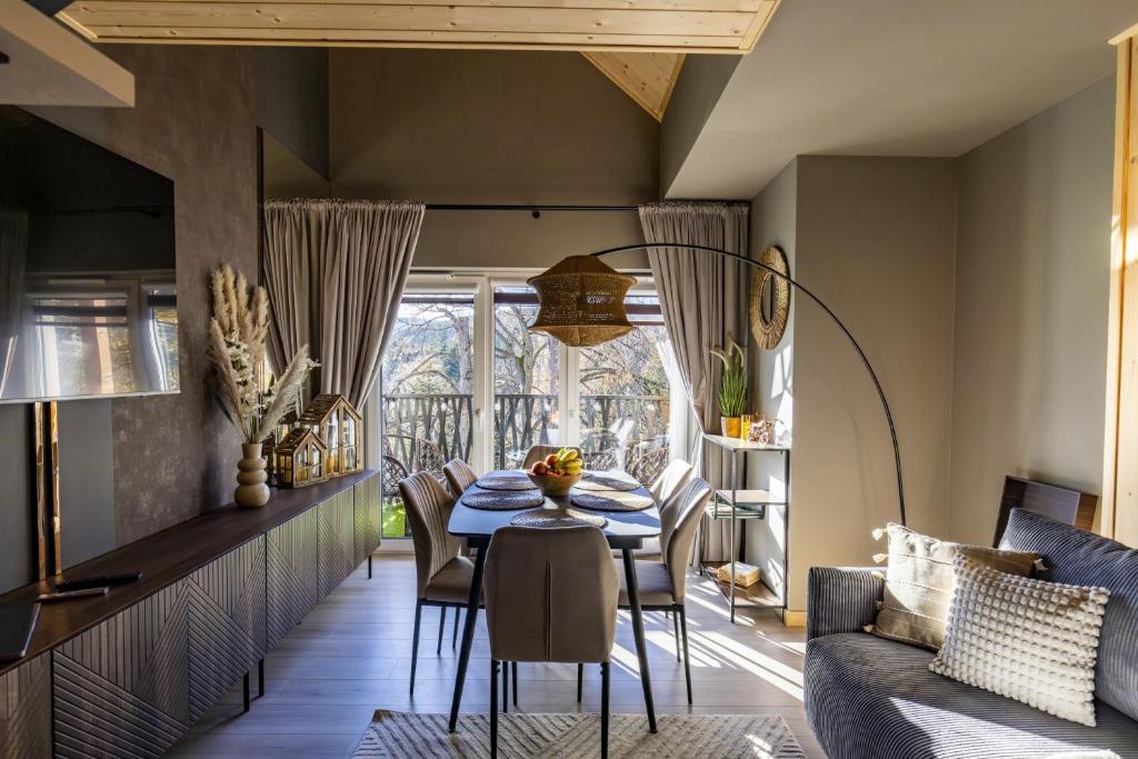 a dining room with a table and a couch at Dolina Szczęścia Apartamenty Pine - Dream Apart in Szklarska Poręba