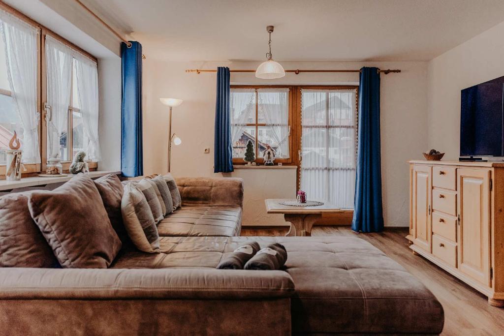 een woonkamer met een bruine bank en blauwe gordijnen bij Gästehaus Wechs in Bad Hindelang