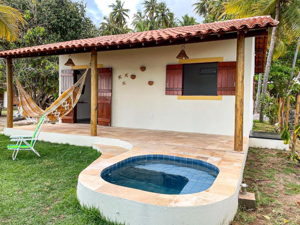 a backyard with a swimming pool and a house at Chalé Refúgio dos Corais 1 in Japaratinga