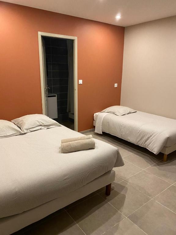 two beds in a room with orange walls at Hôtel La Lavande in Carpentras