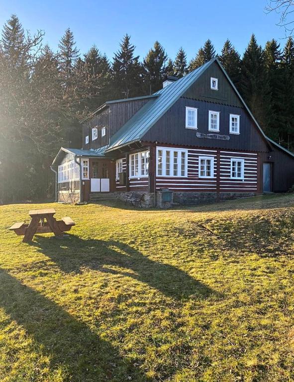 a large wooden barn with a picnic table in front of it at Horská chalupa Rychnovská bouda u skiareálu in Horní Malá Úpa