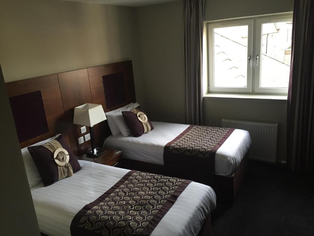 Habitación de hotel con 2 camas y ventana en Buchan Hotel en Ellon