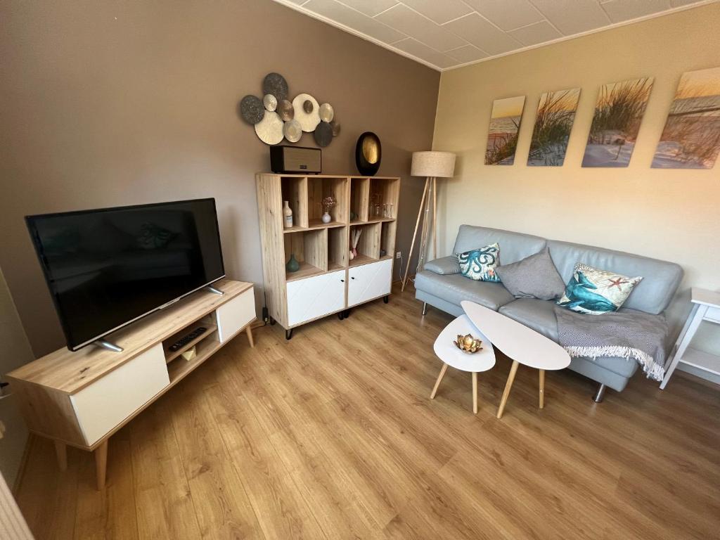 a living room with a couch and a flat screen tv at Hooge Hörn Bantje Wohnung 3 in Borkum