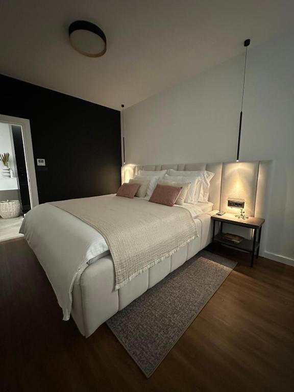 a bedroom with a large white bed and a table at Centar Residence in Slavonski Brod