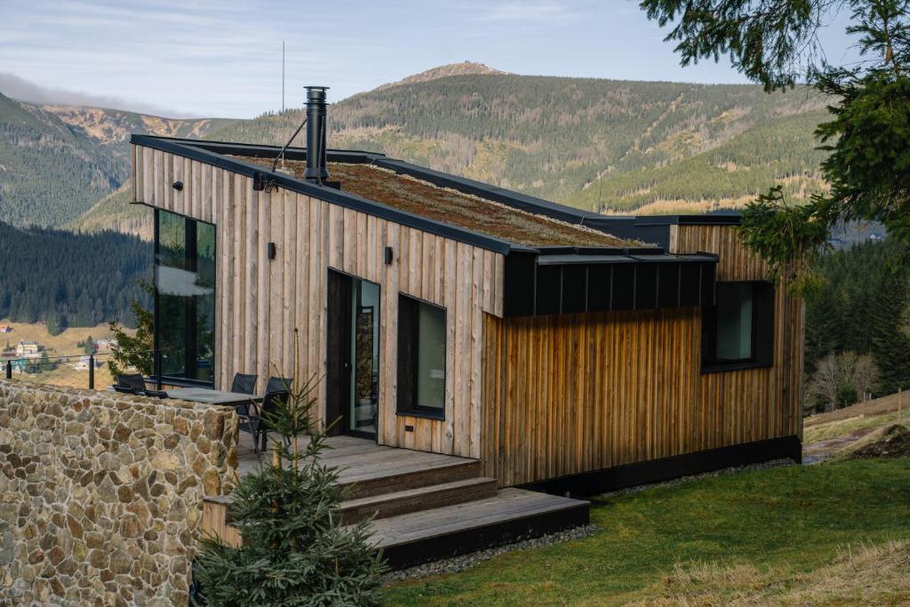 a house on a hill with mountains in the background at Chalet Paseka in Pec pod Sněžkou