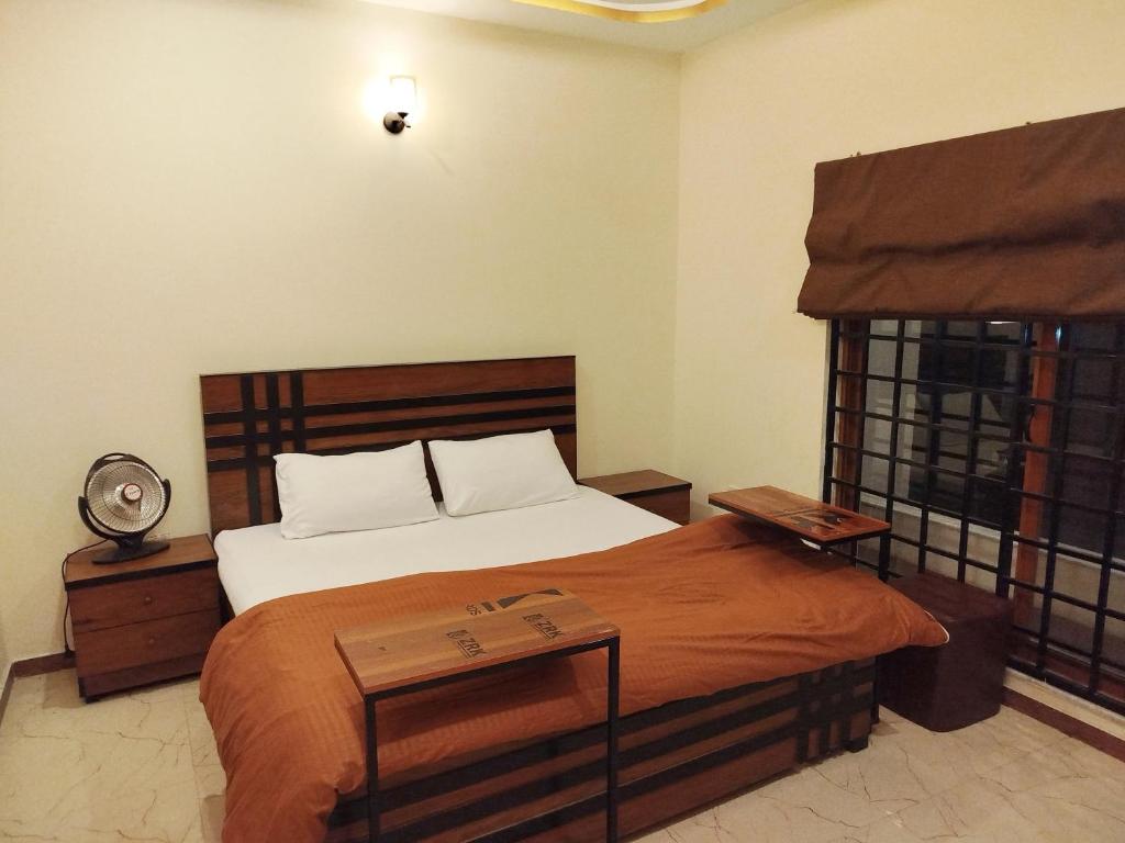 a bedroom with a large bed with a wooden headboard at The Warmer House Islamabad Airport in Islamabad
