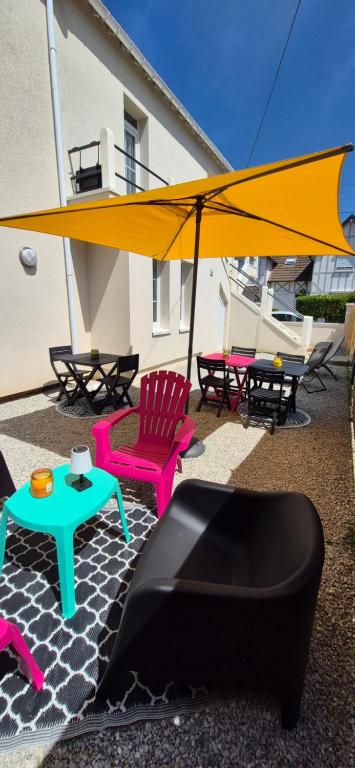 a patio with chairs and a large yellow umbrella at L'Espadon in Luc-sur-Mer