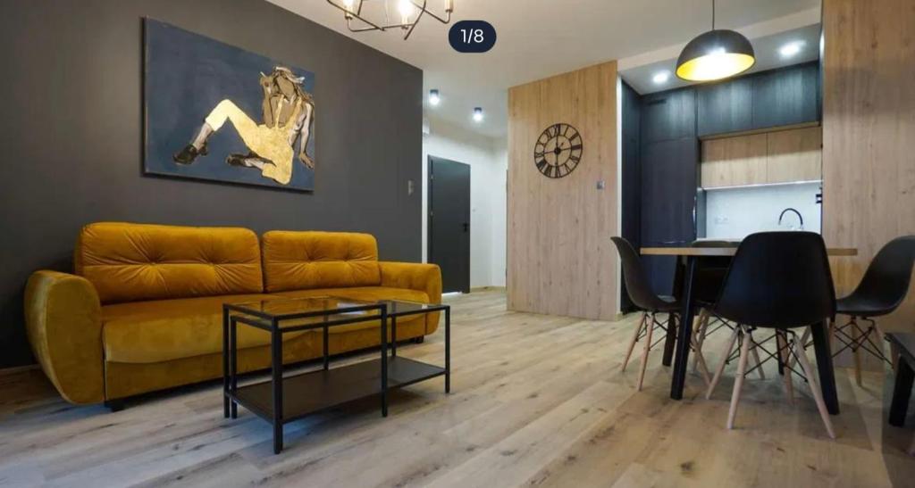 een woonkamer met een gele bank en een tafel bij Apartament Jurowiecka 17 in Białystok