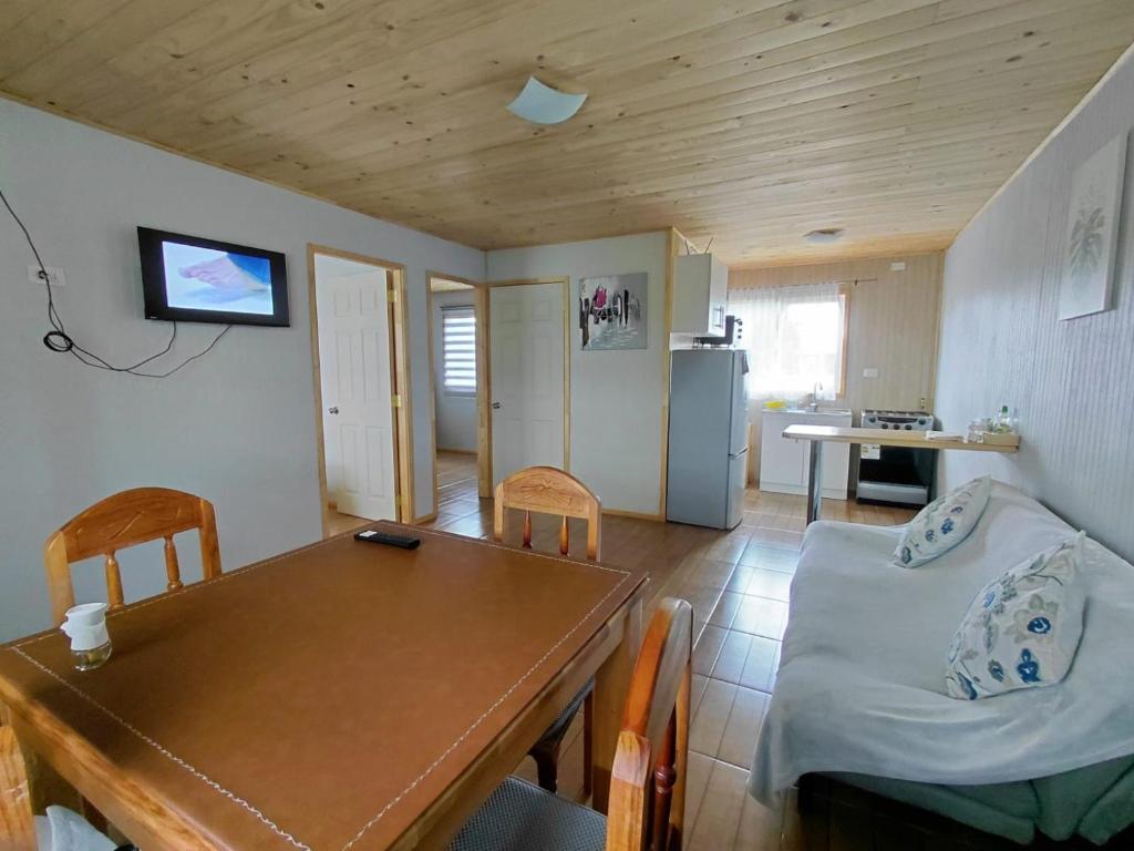 a kitchen and dining room with a table and a couch at Cabaña Aeropuerto el Tepual in Puerto Montt