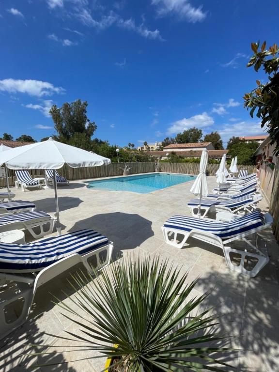 a group of chairs and umbrellas next to a swimming pool at Le Râteau Bavoir in Calvi