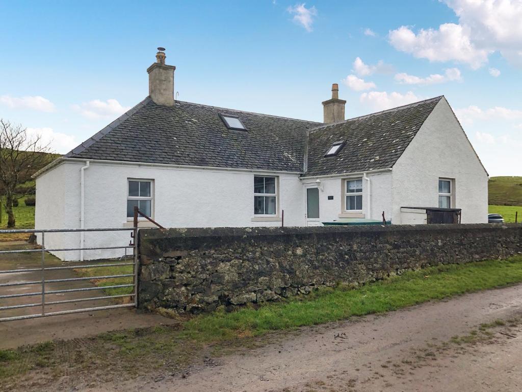 ein weißes Haus mit einer Steinmauer in der Unterkunft Ballygroggan Cottage - Uk48768 in Machrihanish