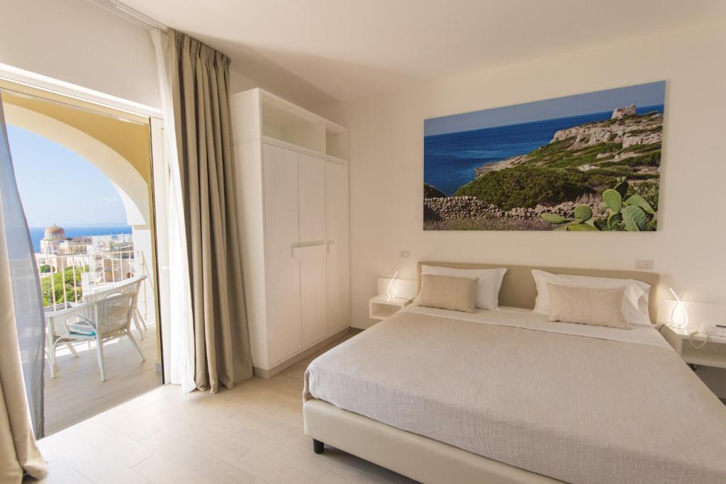 a white bedroom with a bed and a balcony at Est hotel in Santa Cesarea Terme