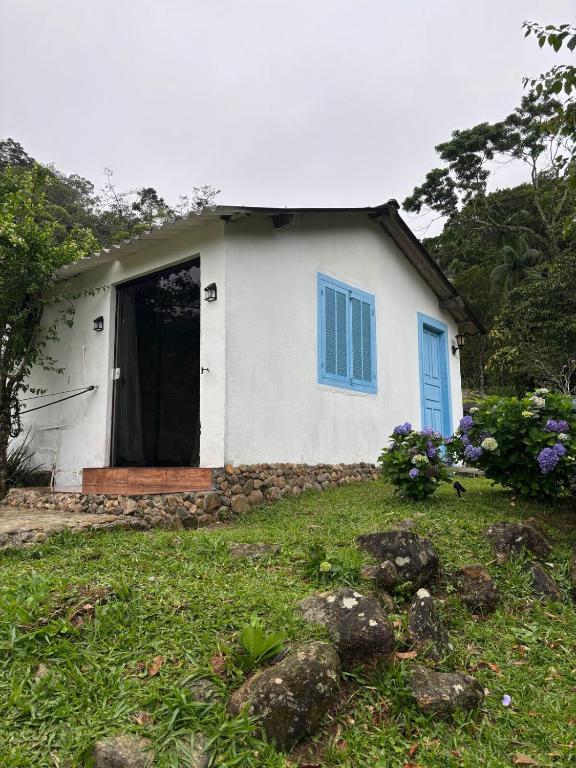a small white house with a blue door at Chácara do Conde in Mangaratiba